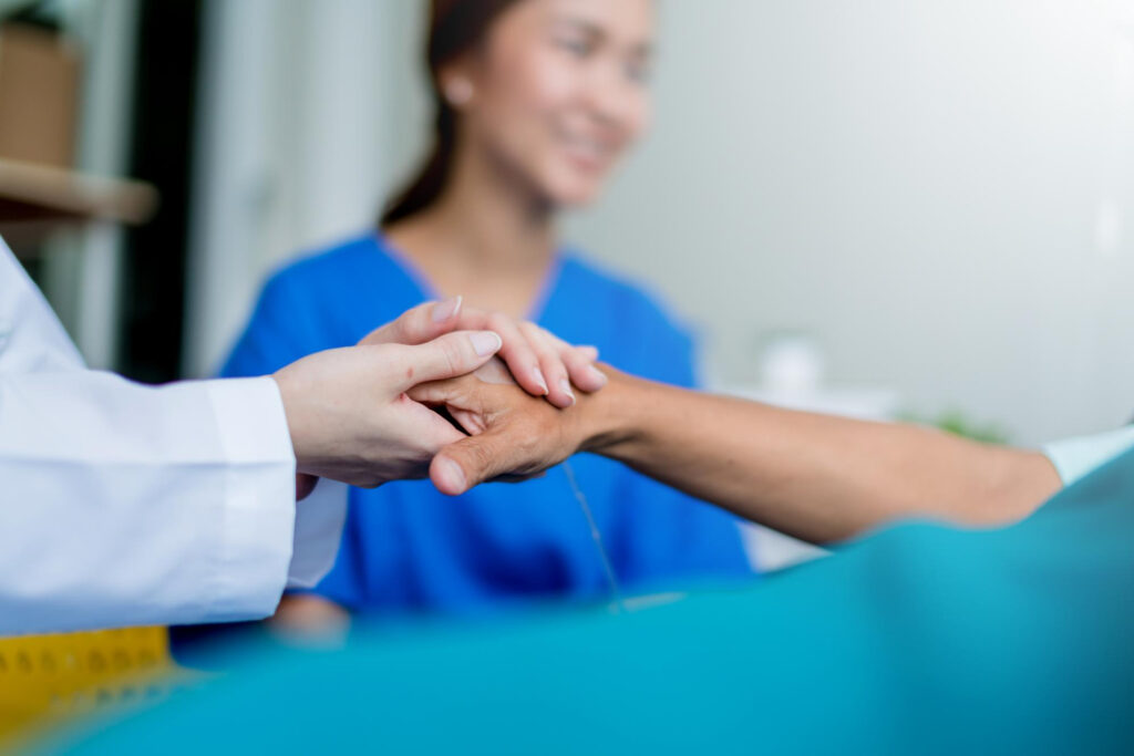 Doctor holding a patient’s hand to offer reassurance after stroke symptoms
