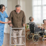 Nurse helping an elderly stroke survivor walk with a walking frame during stroke recovery