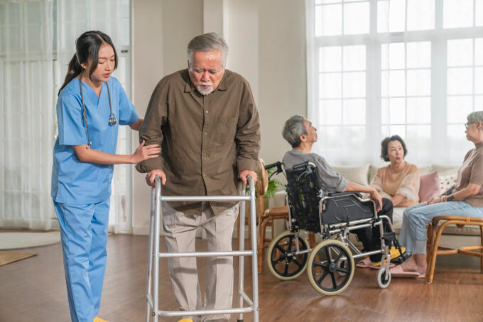 Nurse helping an elderly stroke survivor walk with a walking frame during stroke recovery