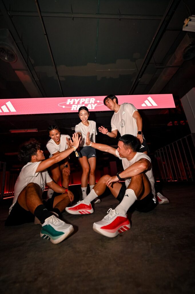 adidas Hybrid Squad runners high-fiving under the Hyperrelay LED banner