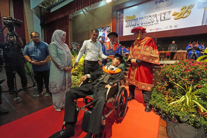 Muhammad Afiq Mohd Hairul Fahmy in a wheelchair with his parents receiving his degree at the UC TATI convocation