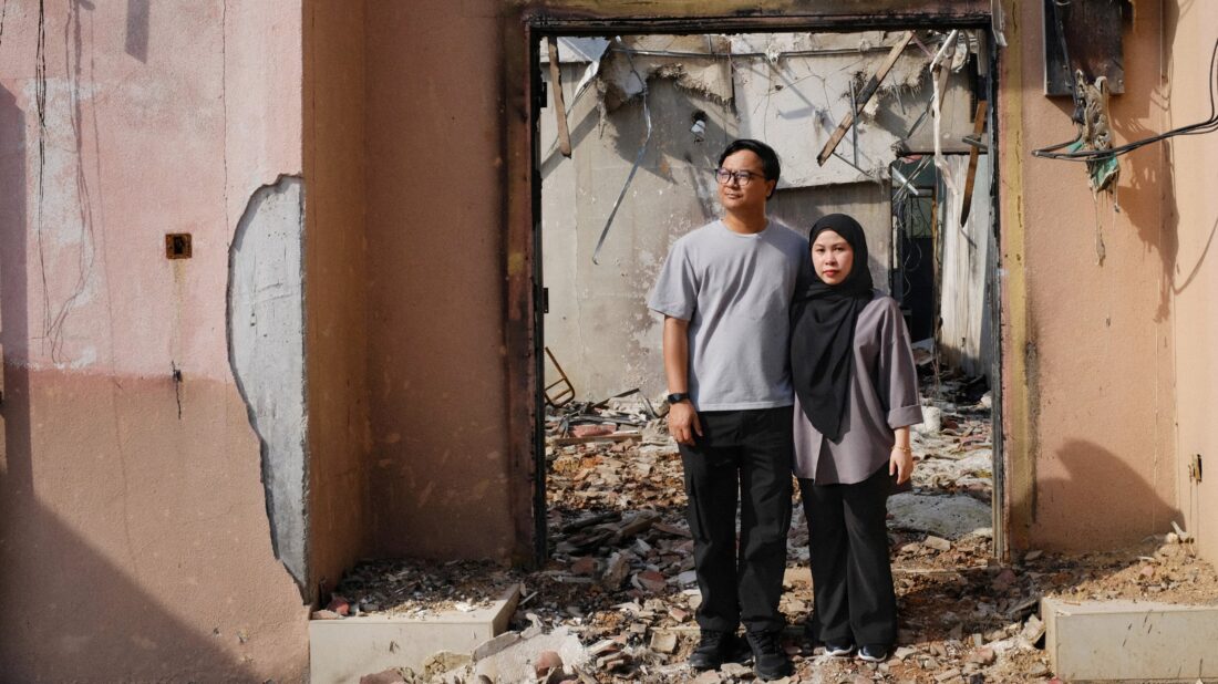 Amirul and Izzati stand outside their fire-damaged Putra Heights home after finding an Airbnb.org stay