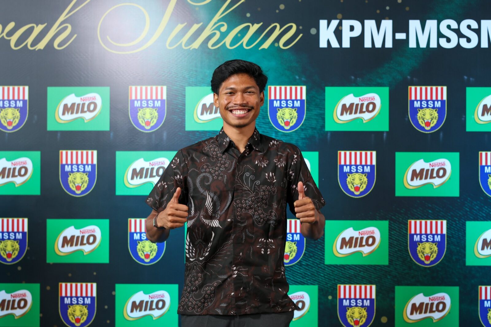 Azeem Fahmi, MILO Malaysia sports ambassador, giving a thumbs up in front of a MILO and MSSM backdrop
