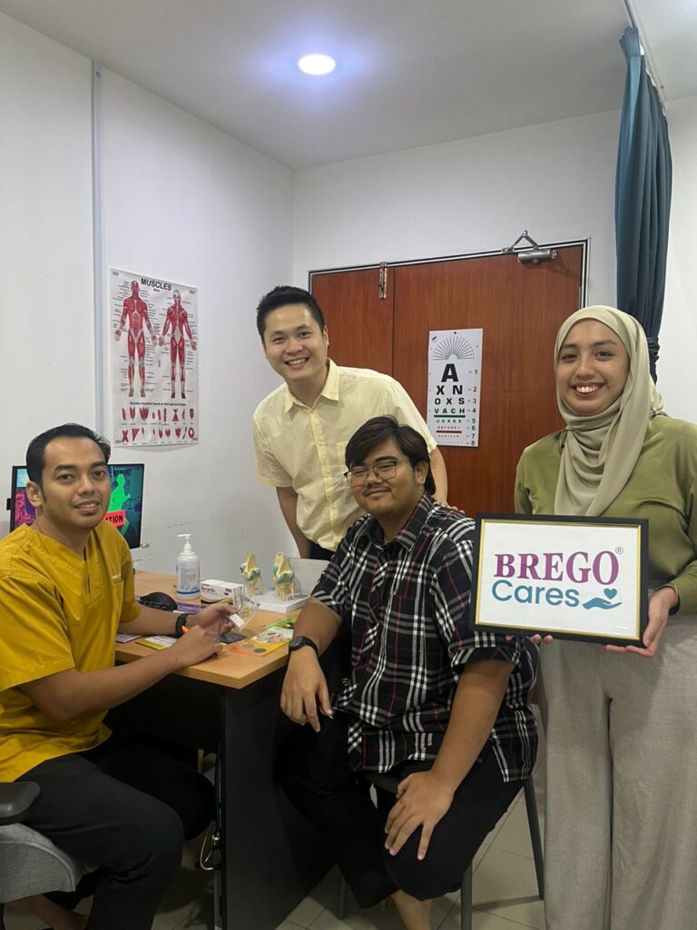 Doctor and participants with a BREGO Cares sign at a primary care clinic consultation room