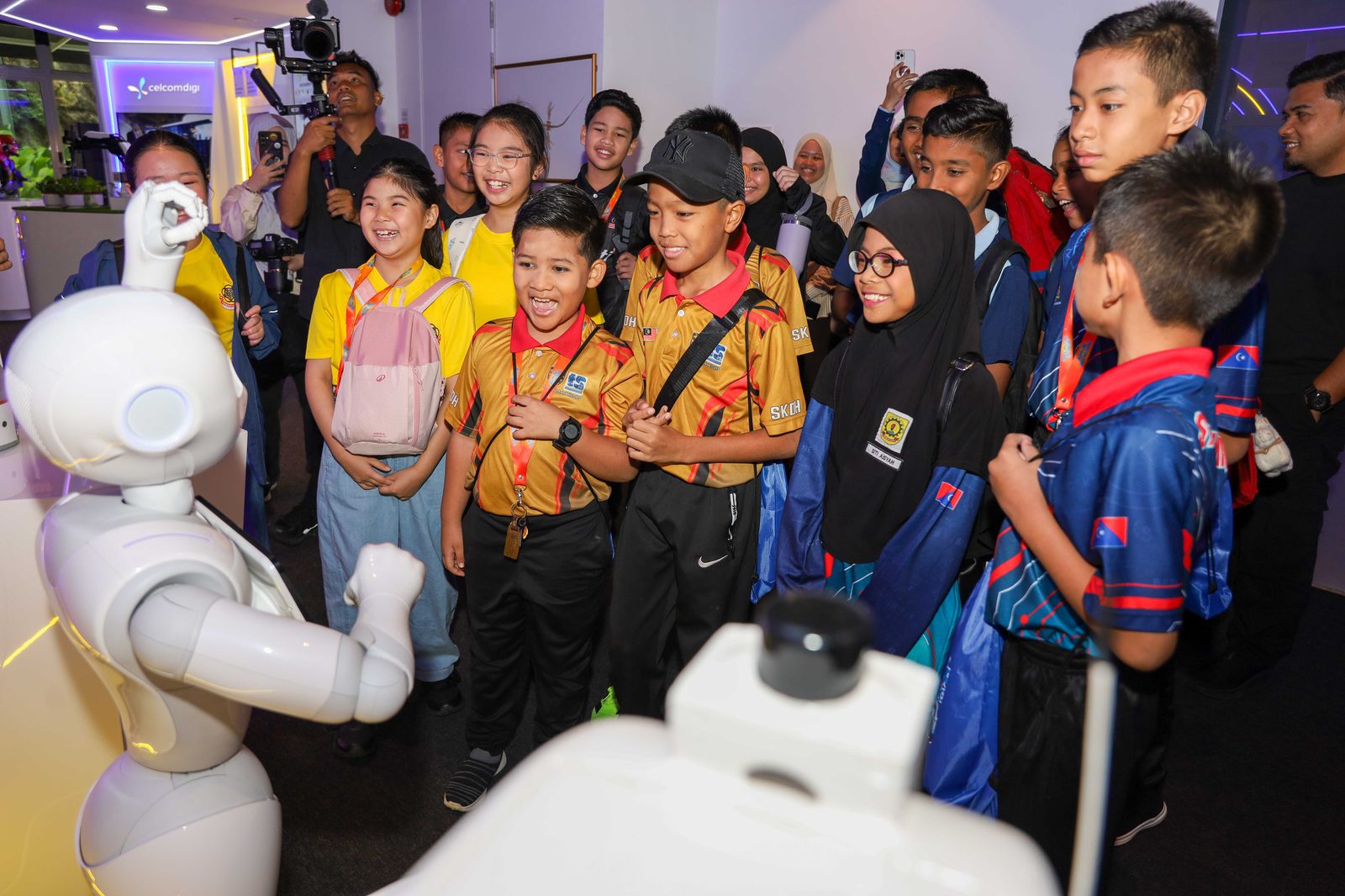 Junior Innovathon 2026 students meeting a humanoid robot at CelcomDigi AiX