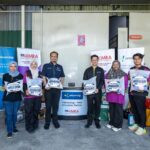 CelcomDigi monsoon preparedness team with Malaysian Relief Agency volunteers holding flood relief kits