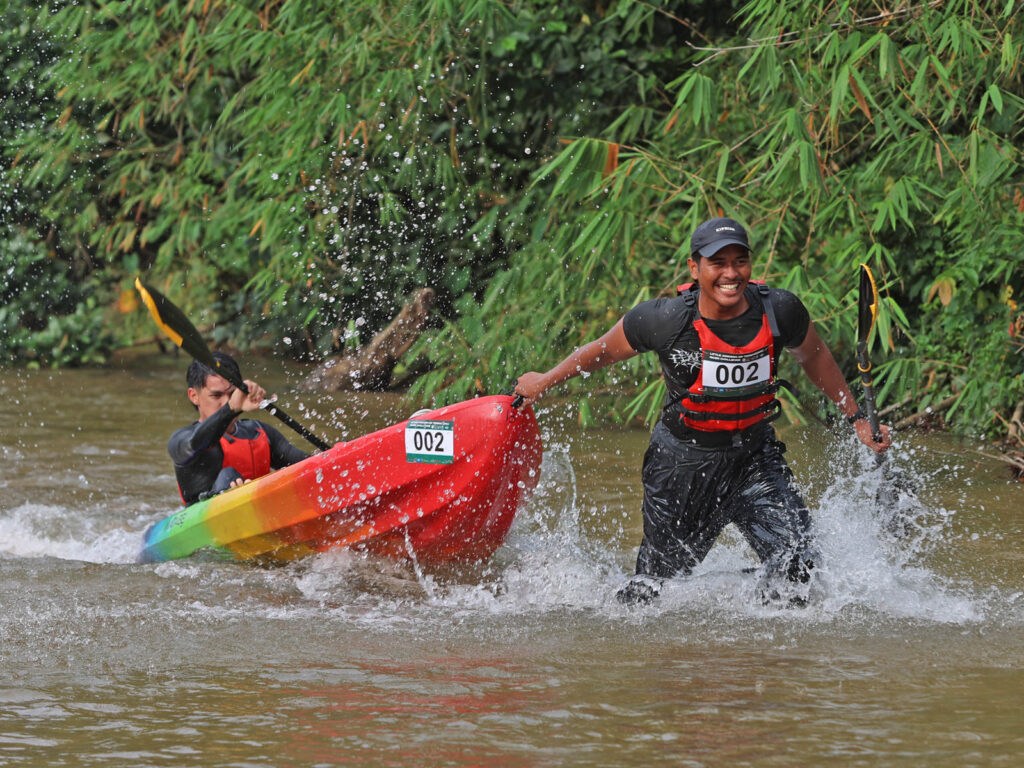 Home team paddlers hauling their kayak through a shallow stretch of Sungai Berang in Hulu Berang