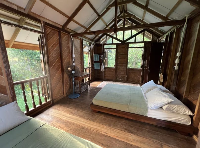 Bedroom inside the Roots & Rimba kampung-style cabin with forest views