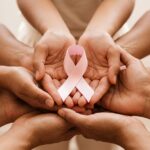 Hands holding a pink ribbon for breast cancer awareness during Pinktober