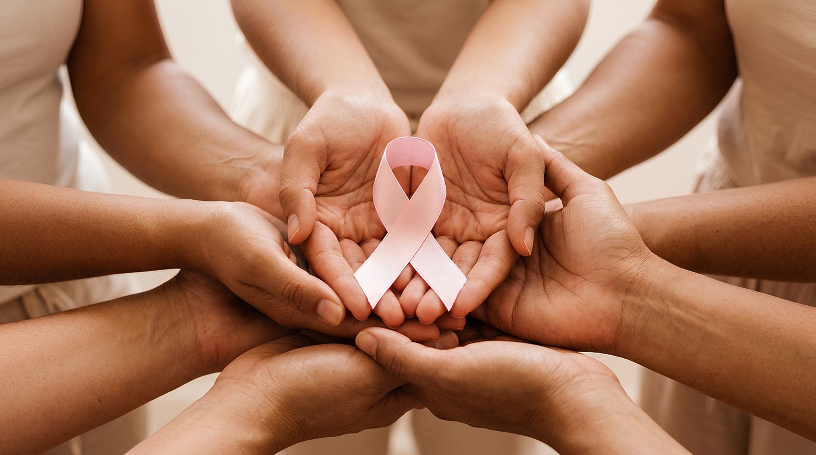 Hands holding a pink ribbon for breast cancer awareness during Pinktober