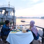 Couple enjoying a Siak Eco Wonders riverside dinner by the Siak River at sunset