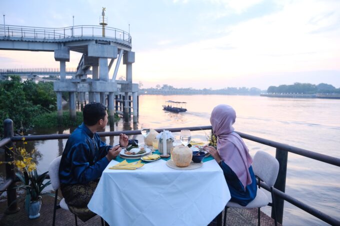 Couple enjoying a Siak Eco Wonders riverside dinner by the Siak River at sunset