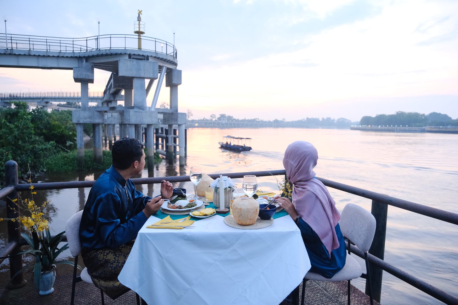 Couple enjoying a Siak Eco Wonders riverside dinner by the Siak River at sunset