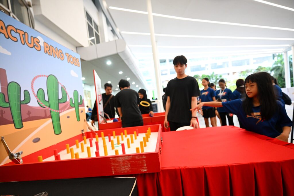 Young participant playing the cactus ring toss carnival game at SJMC Run 2026