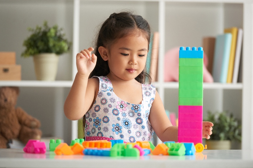 Young girl stacking colourful toy blocks, a simple play activity that supports toddler brain development