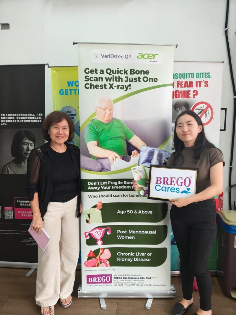 Two women holding a BREGO Cares sign beside a VeriOsteo OP AI-assisted bone health screening banner