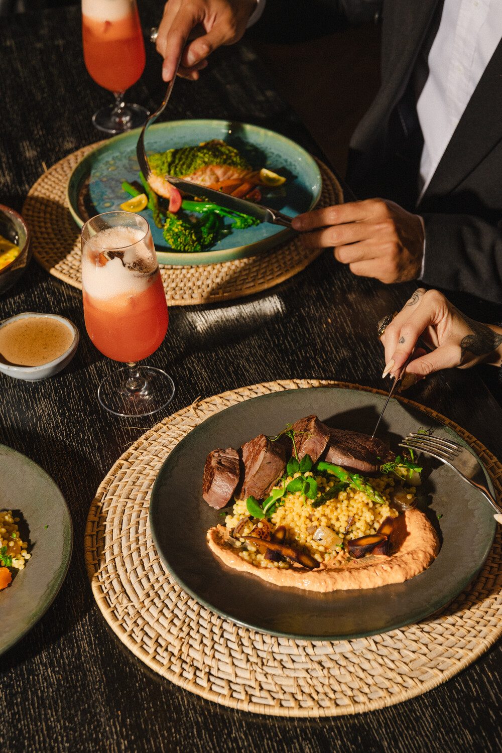 Beef tenderloin with pearl couscous and herb-crusted salmon served with pink cocktails